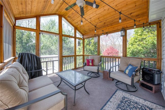 Screened in porch with wooded view, stairs leading to the backyard. | Image 27