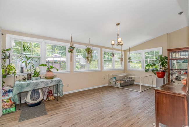 Sunroom / solarium with wood finished floors, a chandelier, lofted ceiling, and a deck | Image 6