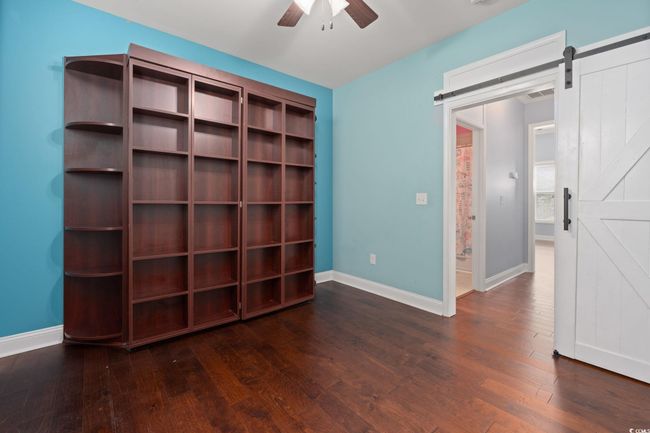 Interior space featuring ceiling fan, wood finished floors, a barn door, and baseboards | Image 26