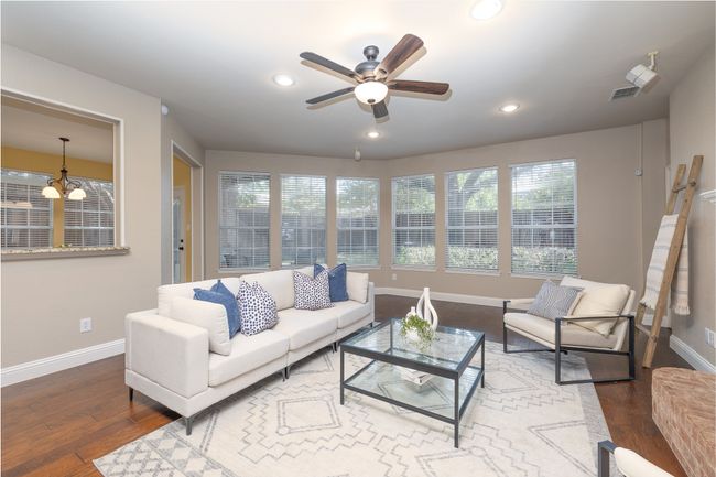 Living area with a ceiling fan, wood finished floors, recessed lighting, and a chandelier | Image 9
