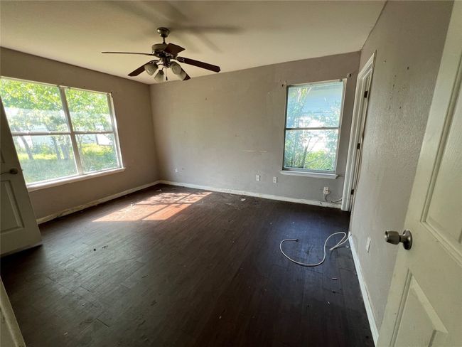 Empty room with dark wood-type flooring, baseboards, and ceiling fan | Image 13