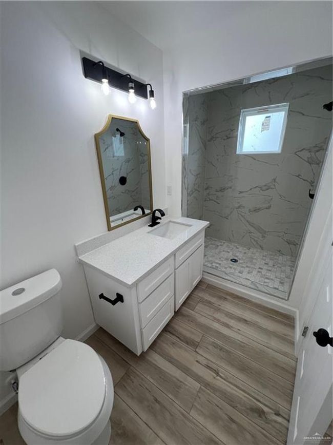 Full bath 2 with toilet, wood finished floors, vanity, baseboards, and a walk in shower | Image 9