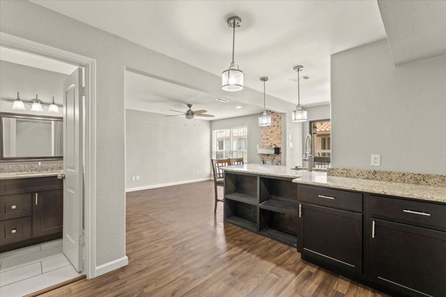 Kitchen with light wood finished floors, open shelves, ceiling fan, and light stone countertops | Image 11