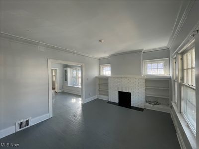 Unfurnished living room with dark hardwood / wood-style flooring, crown molding, and plenty of natural light | Image 2