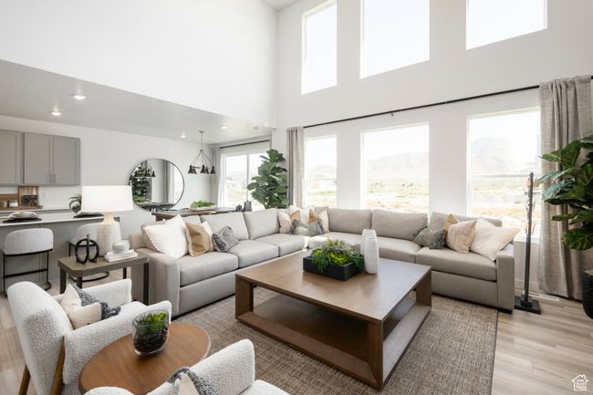 Living room with light wood-type flooring, a towering ceiling, and recessed lighting | Image 7