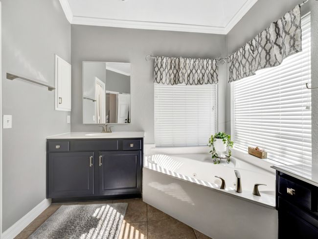 Bathroom featuring a jetted garden tub, crown molding, vanity, baseboards, and tile floors | Image 25