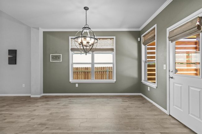 Unfurnished dining area with a chandelier, crown molding, wood finished floors, and baseboards | Image 14
