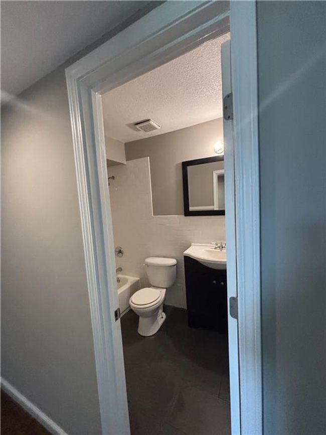 Full bathroom featuring tile walls, vanity, toilet, bathtub / shower combination, and a textured ceiling | Image 25