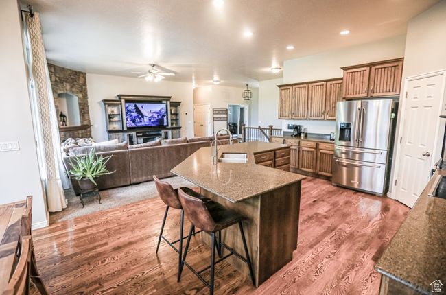 Kitchen featuring stainless steel fridge with ice dispenser, a sink, a ceiling fan, wood finished floors, and a breakfast bar area | Image 8