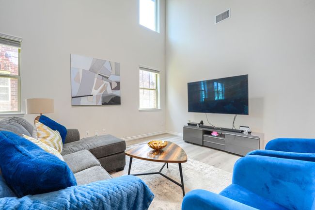 Living area with plenty of natural light, light wood-type flooring, baseboards, and a towering ceiling | Image 7