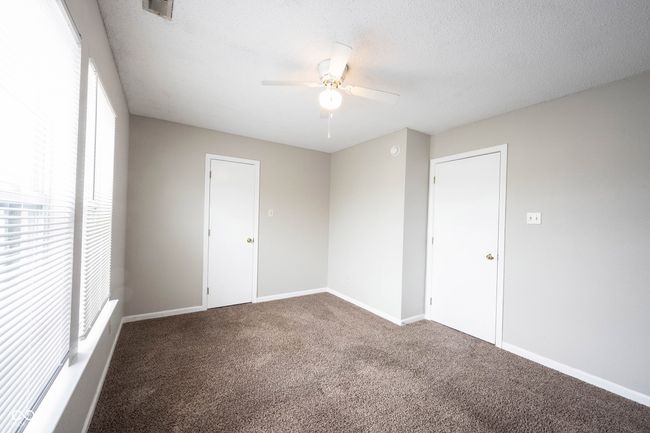 carpeted empty room featuring baseboards, a ceiling fan, and visible vents | Image 23