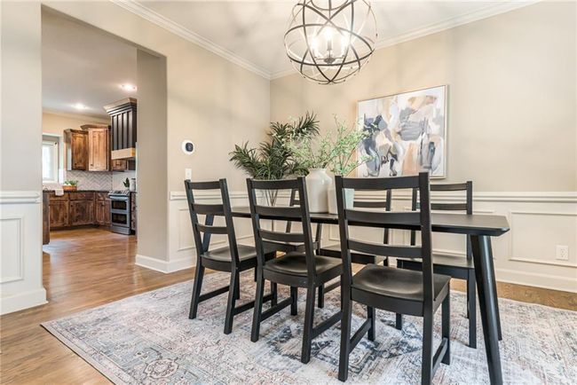 Dining space featuring a chandelier, crown molding, light wood-style floors, and wainscoting | Image 6