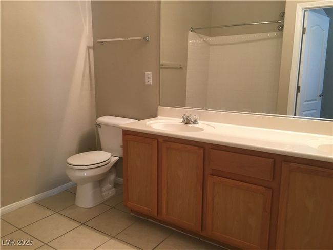 Bathroom featuring tile patterned floors, double vanity, toilet, and a shower | Image 4