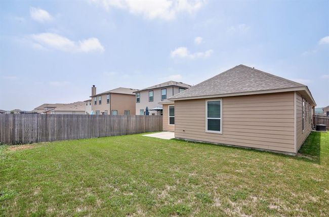Rear view of house with a fenced backyard, roof with shingles, a patio, and a residential view | Image 25