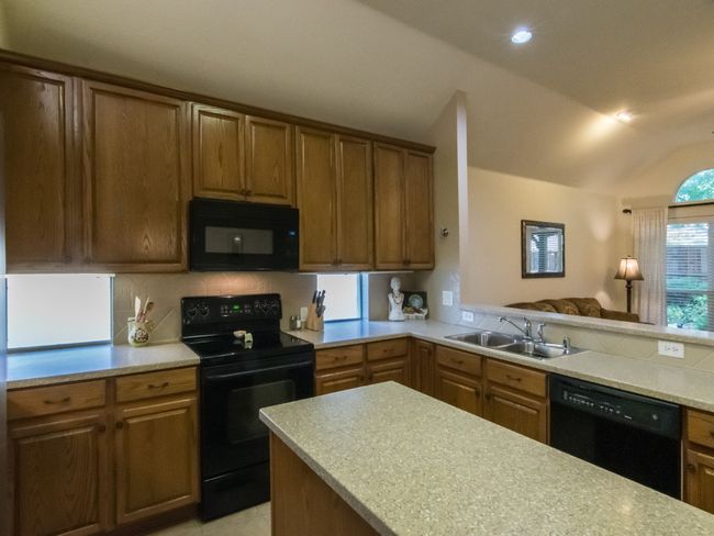 Spacious kitchen features tons of cabinet storage, center work island, breakfast bar counter, and over looks casual family living area. | Image 8