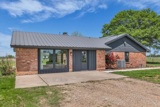 Back of house featuring brick siding, central AC, and metal roof | Image 9