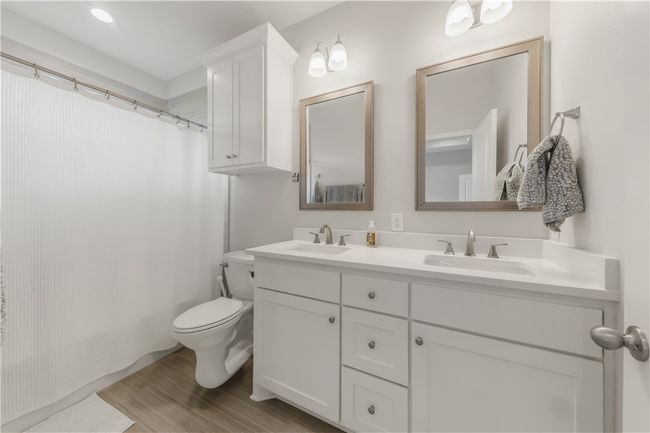 Full bathroom featuring double vanity, wood finished floors, and shower / tub combo | Image 8