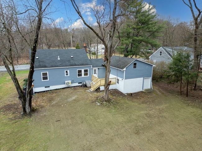 Rear view of house featuring dirt driveway, a shingled roof, and a garage | Image 42