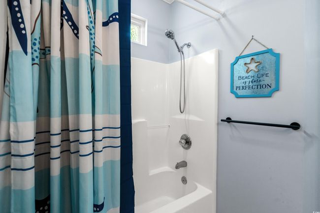 Bathroom with curtained shower, toilet, and vanity | Image 35