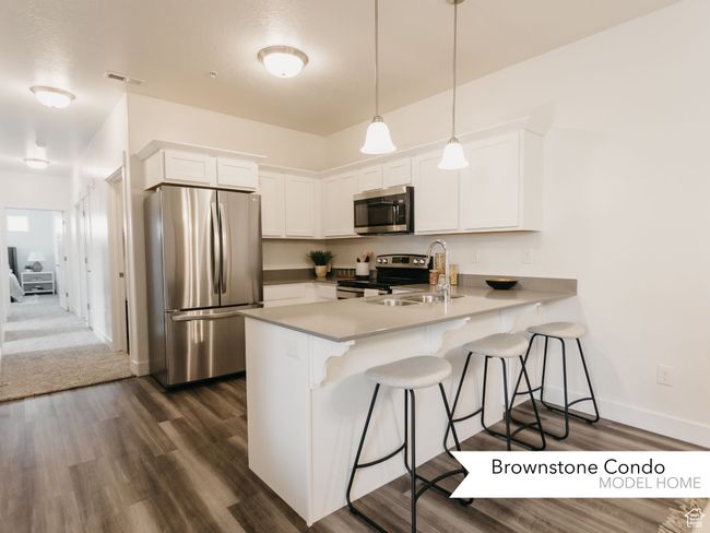 Kitchen featuring a breakfast bar area, stainless steel appliances, white cabinets, a peninsula, and visible vents | Image 9