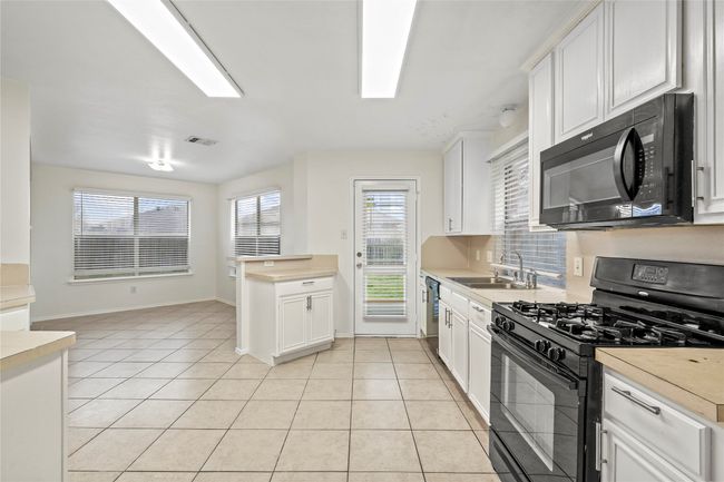 Kitchen featuring a sink, black appliances, light tile patterned flooring, and light countertops | Image 9