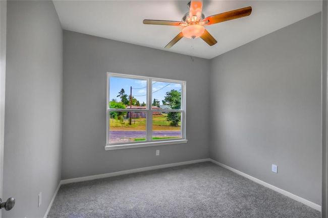 The secondary bedroom with neutral colors, 9' ceiling, ceiling fan and natural light with a view of the front. | Image 13