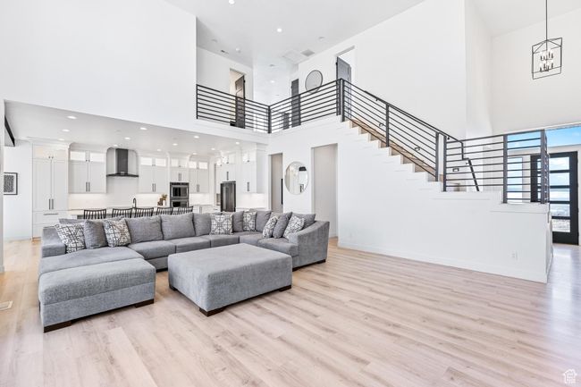 Living area with baseboards, stairway, a high ceiling, and light wood finished floors | Image 13