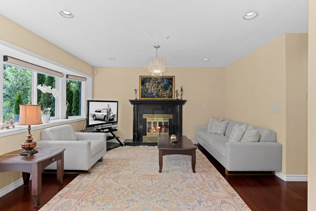 Living area with wood finished floors, recessed lighting, a chandelier, and a glass covered fireplace | Image 13