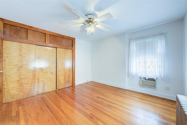 Unfurnished bedroom with radiator, light wood-type flooring, a closet, and a ceiling fan | Image 26