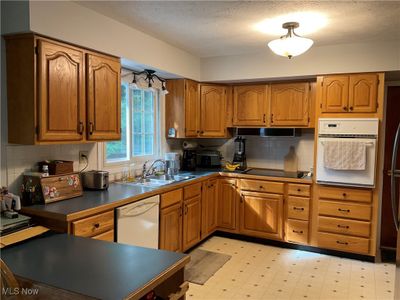 Kitchen with a textured ceiling, backsplash, sink, and white appliances | Image 3