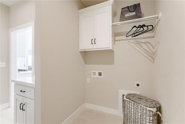 Laundry area with light tile patterned floors, baseboards, hookup for an electric dryer, cabinet space, and hookup for a washing machine | Image 15