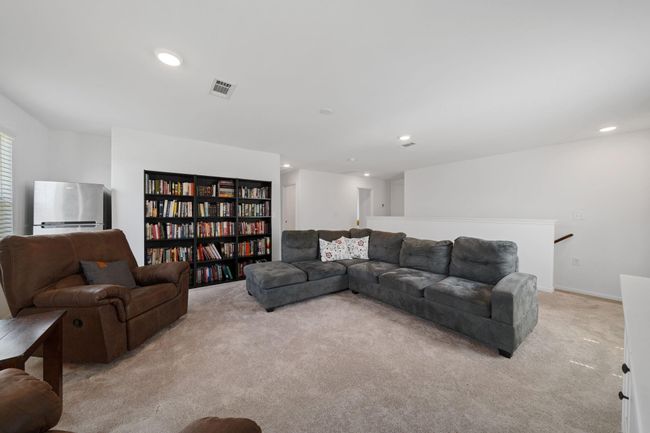 The upstairs living space features soft carpet flooring, a ceiling fan, and a window that brings in natural light. | Image 17
