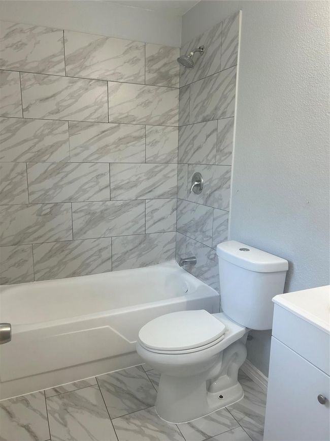 Bathroom featuring marble finish floors, bathing tub / shower combination, toilet, vanity, and baseboards | Image 16
