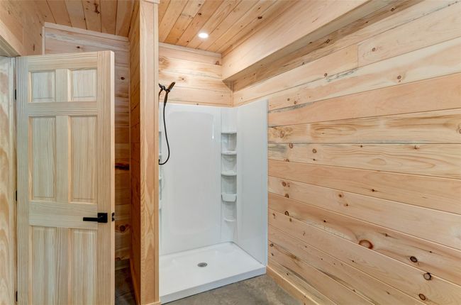Full bathroom featuring wood walls, wooden ceiling, a stall shower, recessed lighting, and concrete floors | Image 37