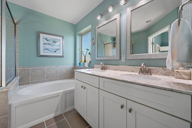 Bathroom with a bath, double vanity, a sink, and visible vents | Image 12