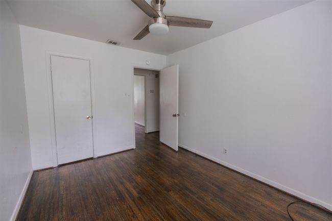 Unfurnished bedroom with baseboards, ceiling fan, dark wood-style floors, and visible vents | Image 7