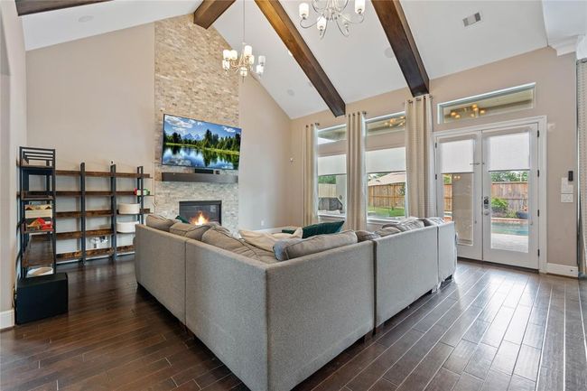 Living area open to the kitchen with vaulted ceiling accented with wooden beams. | Image 10