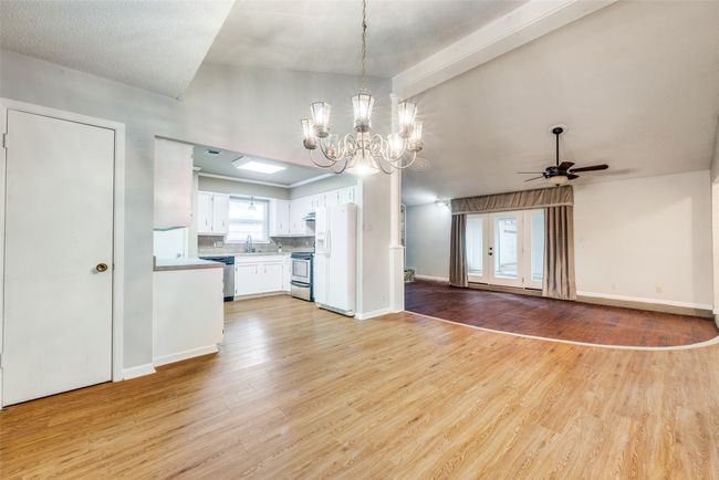 Unfurnished living room featuring a ceiling fan, a sink, light wood-style flooring, a chandelier, and baseboards | Image 7