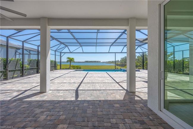 View of patio / terrace with glass enclosure, a pool with connected hot tub, and a water view | Image 26