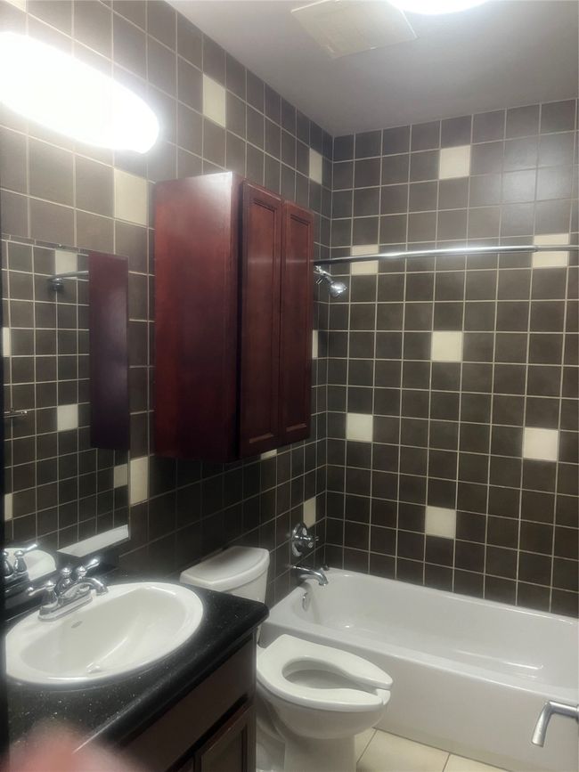 Full bathroom with tile patterned floors, shower / bathtub combination, vanity, tile walls, and toilet | Image 7