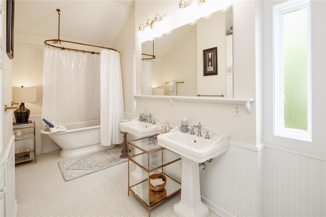 Full bath with a wainscoted wall, shower / tub combo, lofted ceiling, and a sink | Image 24