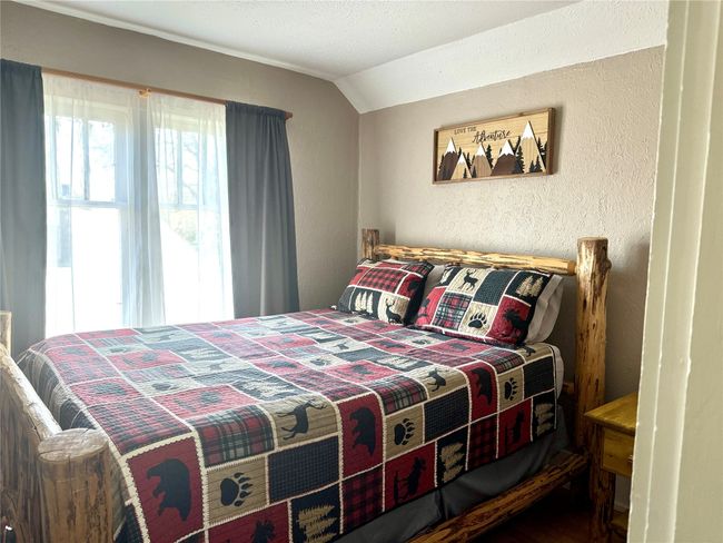 Bedroom featuring lofted ceiling, a textured wall, and wood finished floors | Image 18