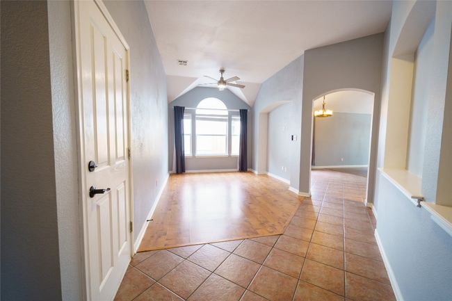 Corridor with arched walkways, tile patterned floors, vaulted ceiling, and baseboards | Image 5