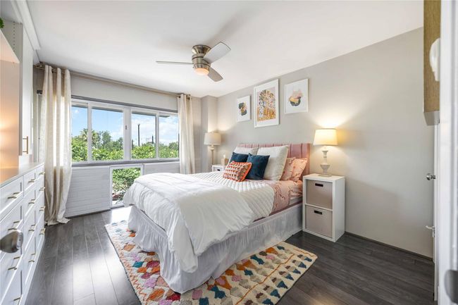 This bright bedroom features a modern design with a large window offering a scenic view and ample natural light. | Image 12