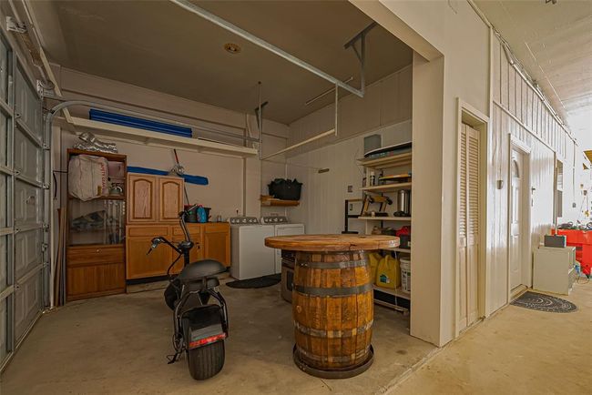 The garage features ample storage with cabinets and shelving, a washer and dryer, and an extra space for a small vehicle or scooter. | Image 39