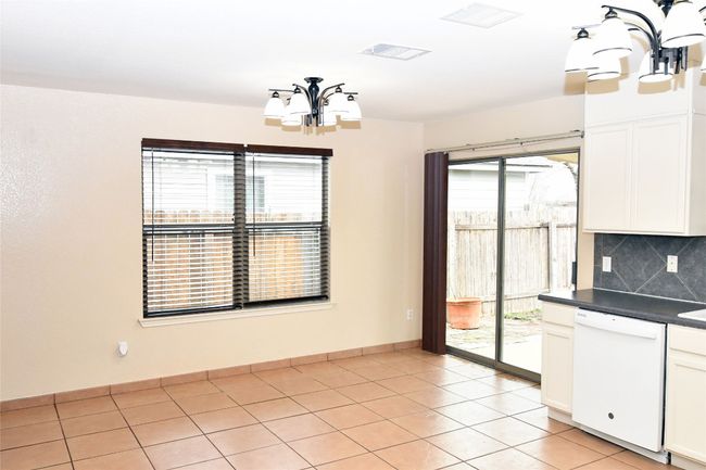 Unfurnished dining area featuring an inviting chandelier, plenty of natural light, visible vents, and light tile patterned flooring | Image 9
