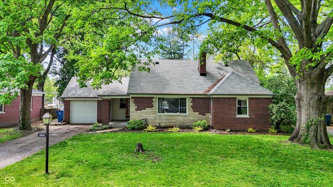 view of front facade featuring an attached garage, asphalt driveway, a front yard, and a chimney | Image 48