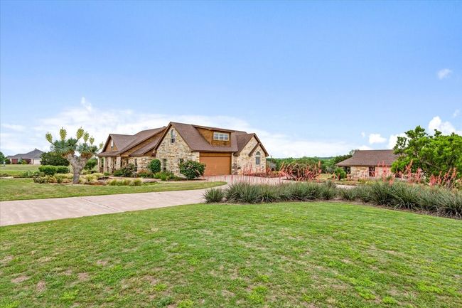 View of front of property featuring stone siding, a garage, a front lawn, and driveway | Image 35