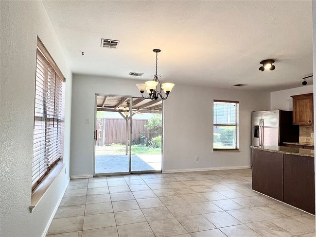 Kitchen with stainless steel fridge, hanging light fixtures, a chandelier, and light tile patterned flooring | Image 10