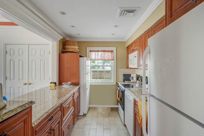 Kitchen featuring white appliances, tasteful backsplash, crown molding, light stone countertops, and recessed lighting | Image 29